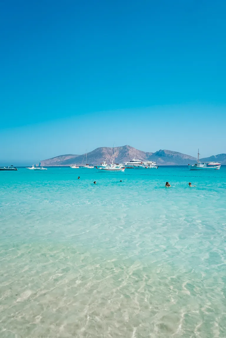 Tourquise water at the beach in Koufonisia with boats and people swimming in the background