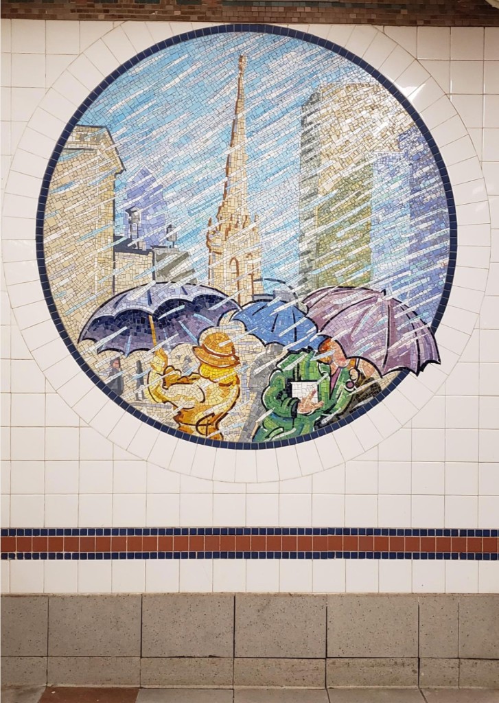 A circular mosaic porthole from Broadway Diary showing pedestrians under purple and blue umbrellas in the rain, with a church spire and city towers behind