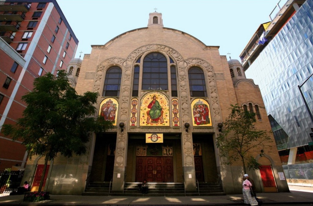 The Byzantine-style facade of St. George Ukrainian Catholic Church on 7th Street, with golden mosaic icons above its carved wooden doors, between a brick apartment block and a glass tower