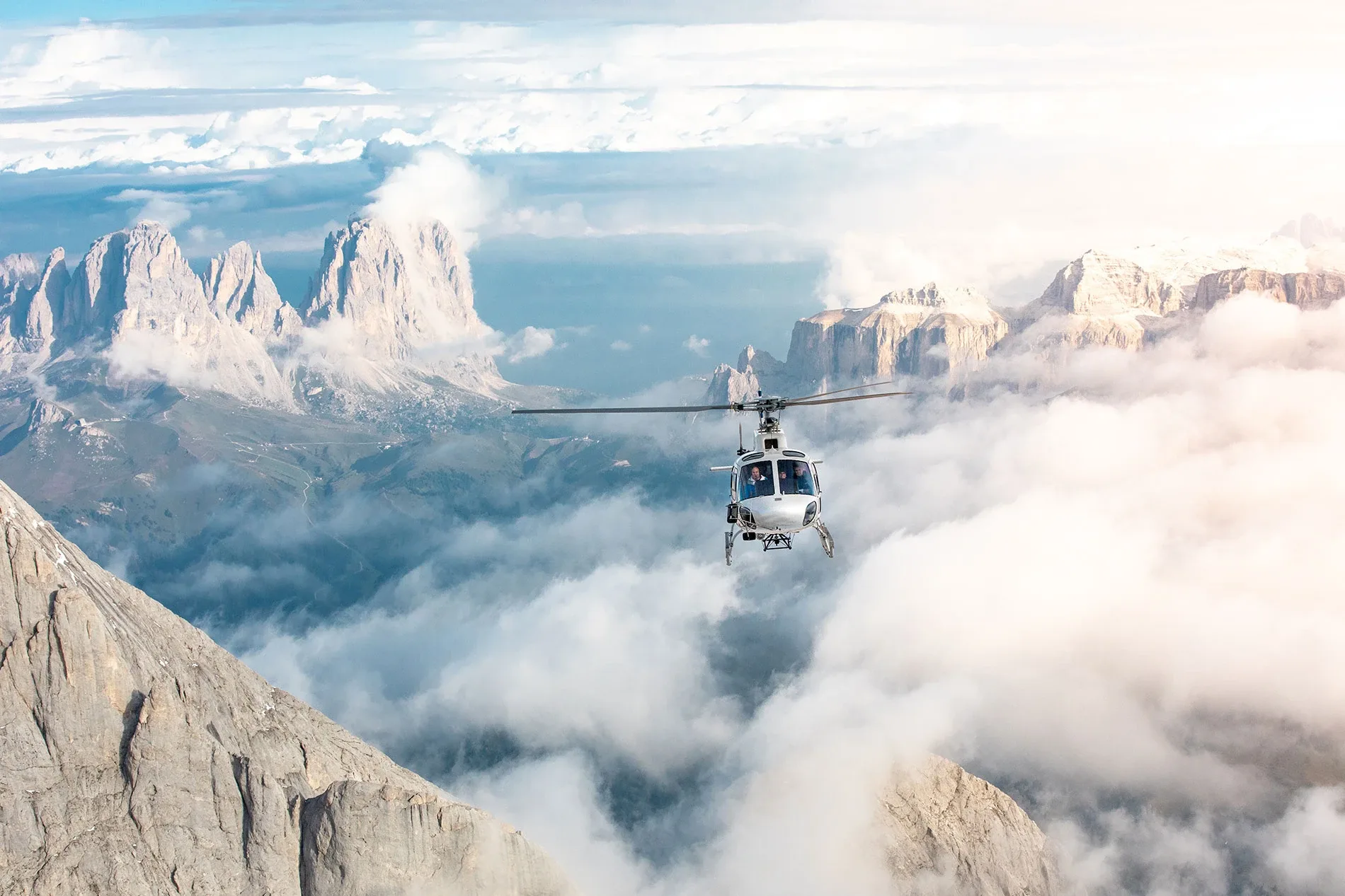 Helicopter flying above clouds with rocky Dolomites mountains in the background